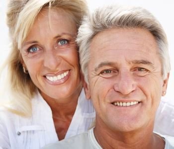 man and woman smiling with beautiful teeth after dental implant from Dr. David Spilkia