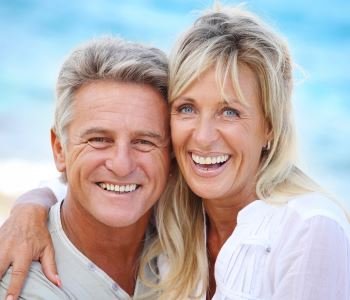 man and woman smiling with beautiful teeth after treatment