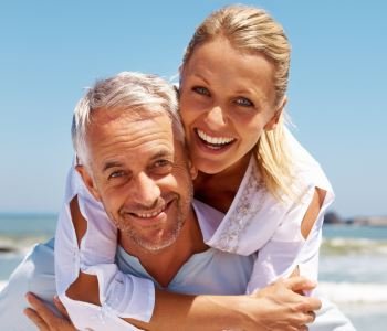 man and woman smiling with beautiful teeth after dental implant