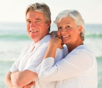 man and woman smiling with beautiful teeth after dental implant